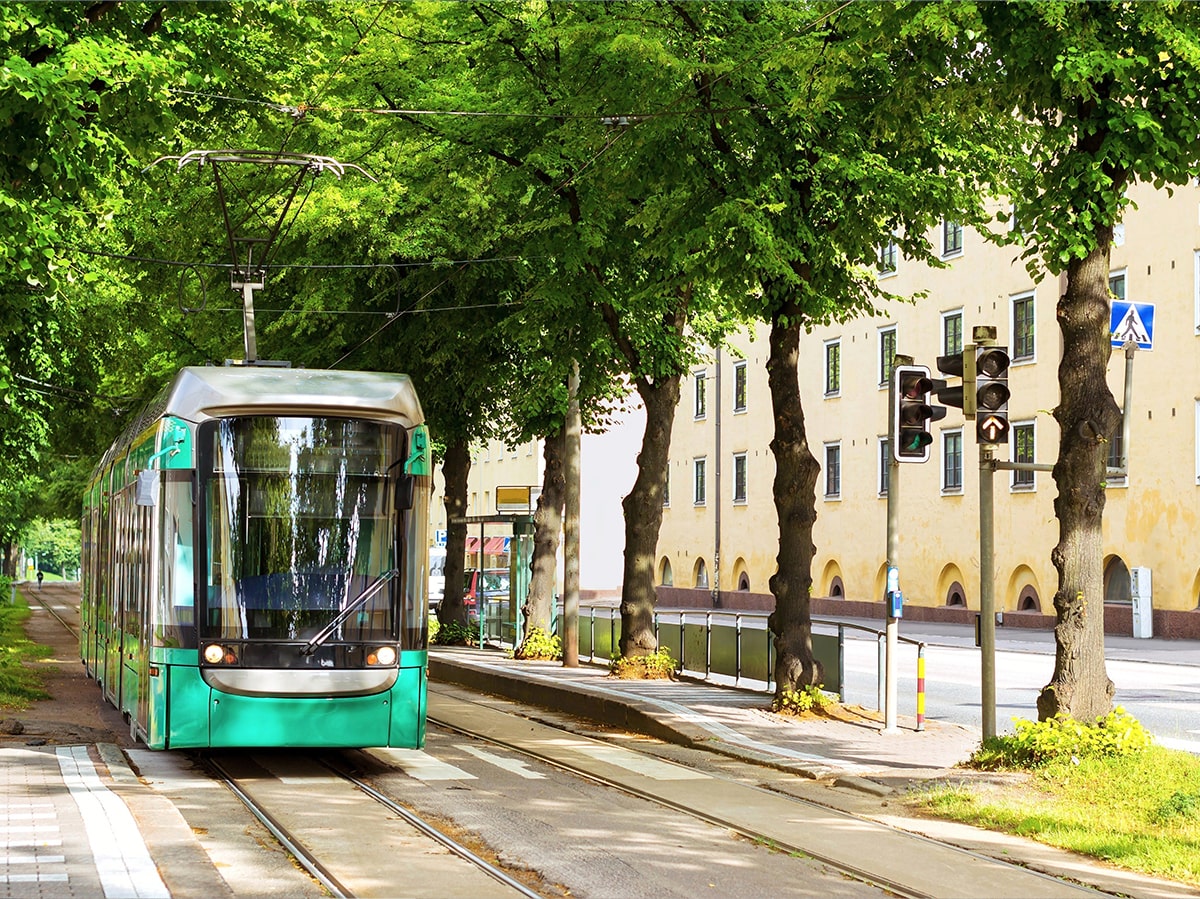 mattersoft-front-page-content-image-2 Modern tram approaching a city stop surrounded by greenery – Mattersoft’s cloud-based public transport software solutions empower well-informed decisions, greener mobility, and smoother journeys for passengers.